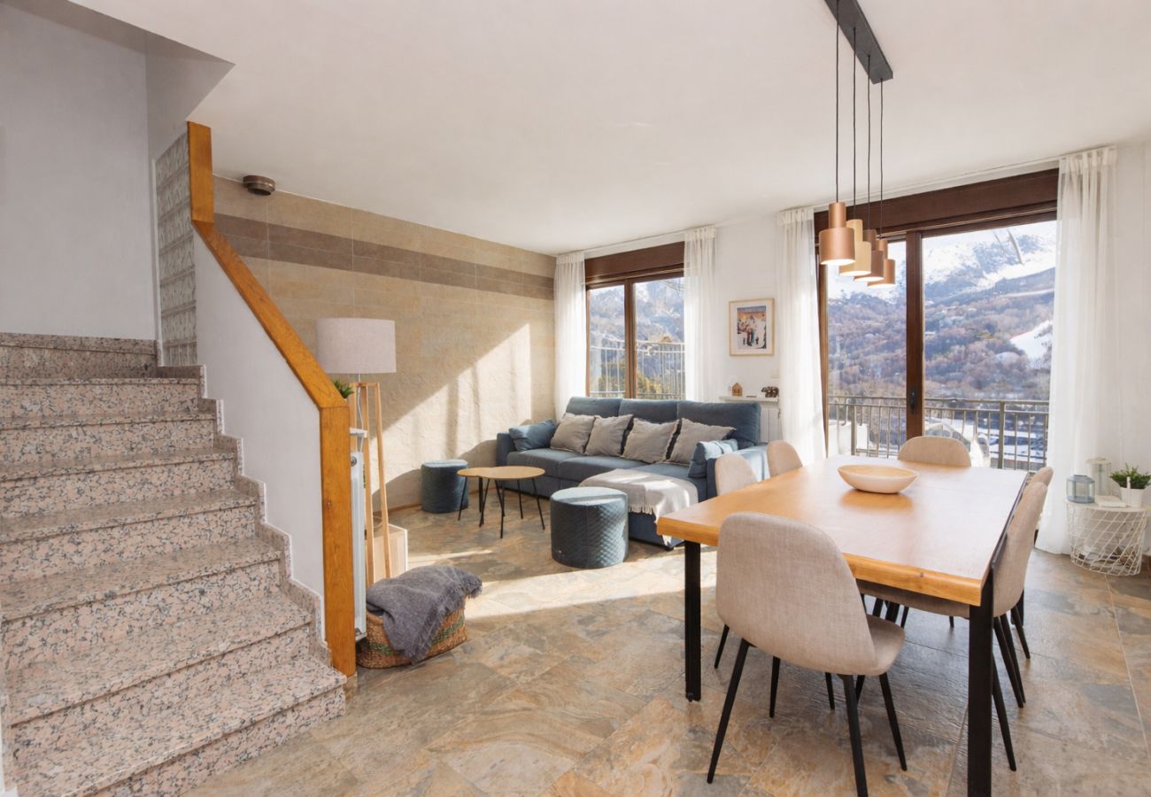 Amplio salón comedor con ventanal y vistas a la montaña en apartamento turístico en Panticosa. 