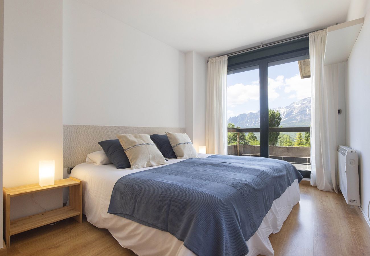 Luminoso dormitorio con cama de matrimonio, decoración cálida y un ambiente ideal para relajarse en Panticosa.