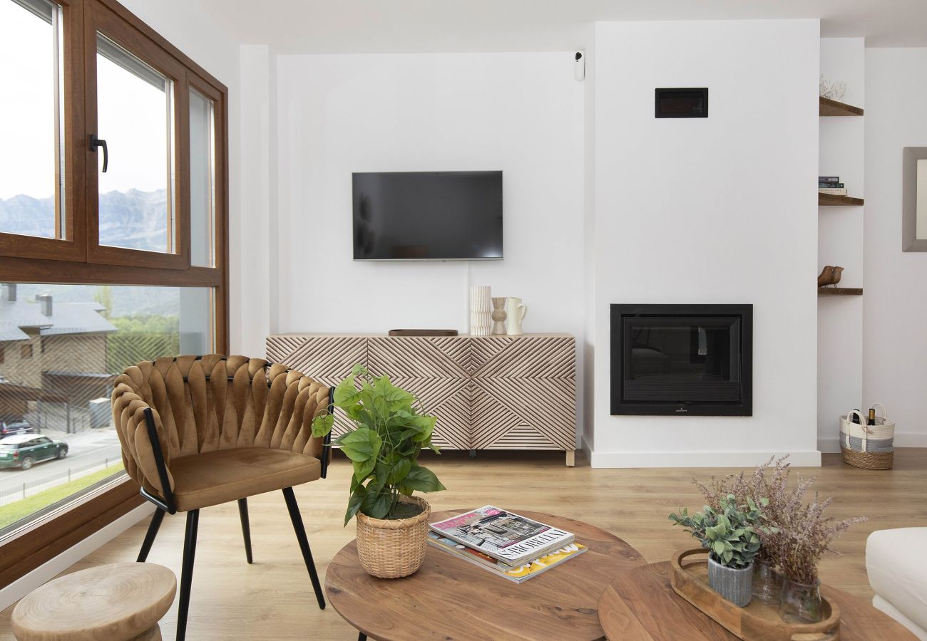 Living room with a large window and natural light in a family apartment in Panticosa.